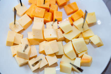 A plate of delicious cheese. Cheddar and mozzarella diced on a white plateの写真素材