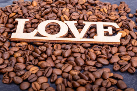 Close-up of coffee beans in the shape of a heart and the inscription love.の写真素材