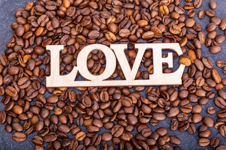 Close-up of coffee beans in the shape of a heart and the inscription love.の写真素材