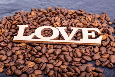 Close-up of coffee beans in the shape of a heart and the inscription love.の写真素材