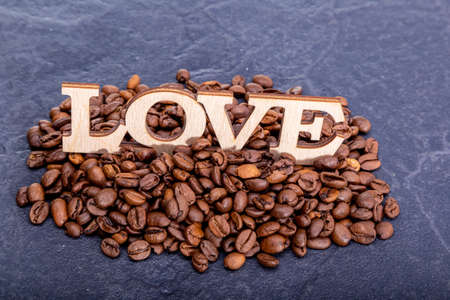 Close-up of coffee beans in the shape of a heart and the inscription love.の写真素材