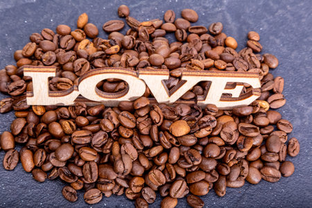 Close-up of coffee beans in the shape of a heart and the inscription love.の写真素材