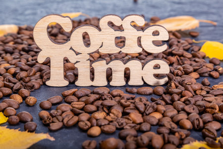 Texture background of coffee beans for design with the description coffee time. Coffee grains scattered on the table.の写真素材