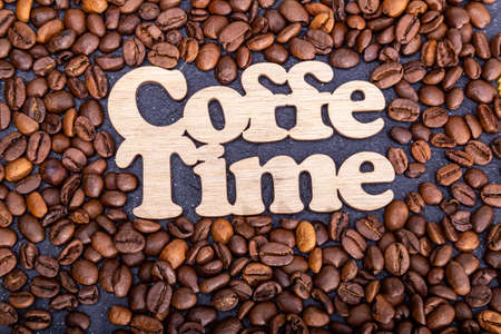 Texture background of coffee beans for design with the inscription coffee time. Coffee grains scattered on the table.の写真素材