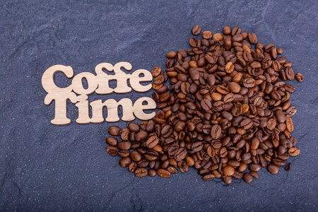Texture background of coffee beans for design with the description coffee time. Coffee grains scattered on the table.の写真素材