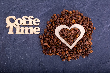 Texture background of coffee beans for design with the inscription coffee time. Coffee grains scattered on the table.の写真素材
