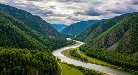 Beautiful winding river flowing through green valley and mountains under cloudy sky.