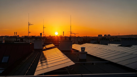 Sunset over city rooftops with solar panels, showcasing sustainable urban livingの写真素材