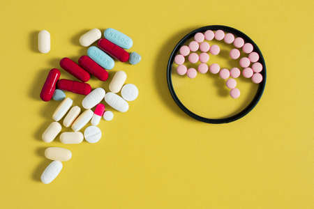 Small round pills simulate brain shape inside a circle and a bunch of different medications on a mustard-colored table. Health care concept.の写真素材