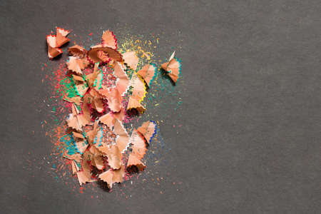 A pile of leftover colored wood of a sharpener pencil on a textured black background. Space to enter text.の写真素材