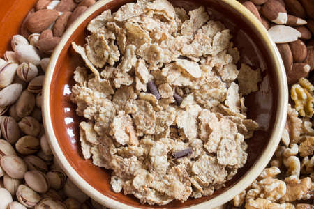 Overhead view of a pile of toasted rice, whole wheat, and barley flakes with chocolate shavings with...