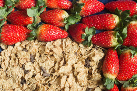 Close-up of a handful of fresh strawberries and whole grains with pieces of dark chocolate. Healthy...