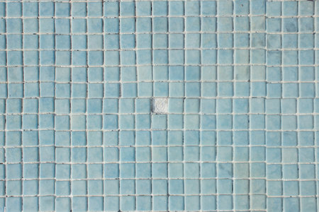 A little hole on the pool floor. Empty stoneware swimming pool floor in which one blue tile is...