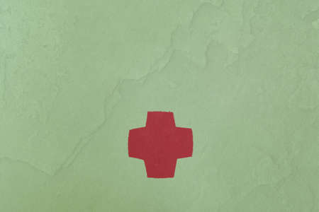 Cross painted on a stone textured paper background with copy space. Medicine health hospital sign or emergency medicine symbol, health care.の写真素材