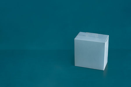 A blank blue square cardboard box on a colorful blue studio background with copy space. Gift,...