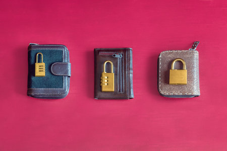 Three different wallets with different golden padlocks and locks on top on a colorful red studio background. Individual and collective economy investments concept.の写真素材