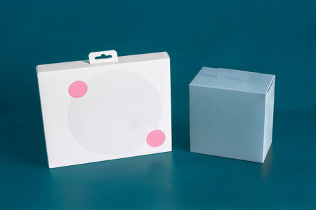 A white cardboard box with two decorative pink circles and a blank blue square box on a colorful...