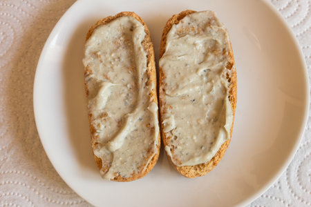 Overhead view of toasted wholemeal rolls spread with Cabrales cheese cream on a plate, accompanied...