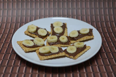 Biscuits with nutella. Chocolate and banana on a background texture.の写真素材