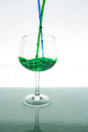 Crystal cup being filled by a blue and green liquidの写真素材