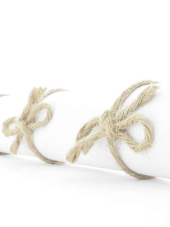 Handmade natural rope knots tied on white letter scroll, isolated