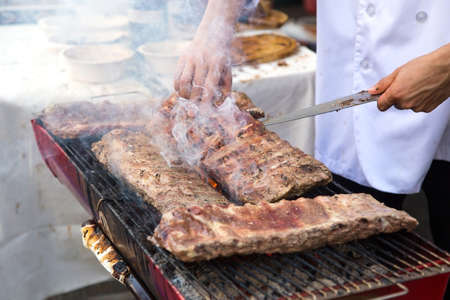 The cook is grilling pork ribs on a hot stove.の写真素材
