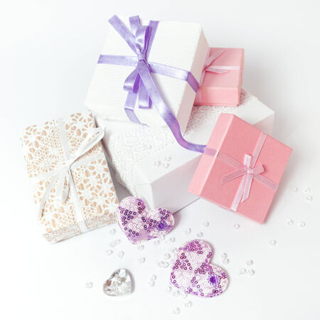 Cute gift boxes in pastel colors on white background. White and pink boxes with bows and ribbons.の写真素材