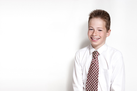 The nice smiling boy teenager in a white shirt and a tie on the white horizontal background with place for textの写真素材