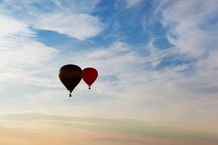 Dark silhouettes of couple flying balloons on the sunset cloudy night skyの写真素材