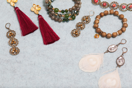 Handmade set of green,golden,bronze,ivory and vinous bijouterie with gems, tassels, cryslals and feathers, lying on the gray wool background, perspective view with empty place for your textの写真素材