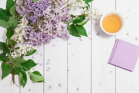 Beautiful lilac flowers with note-book and cup of teaの写真素材