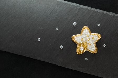 Dark background with handmade brooch golden starの写真素材