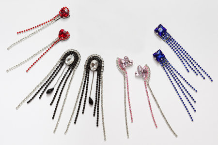 Handmade set of stylish shiny fine earrings with crystals, lying flat on the white background, top view with empty place for your textの写真素材