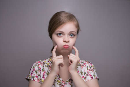 White, cute, caucasian girl upset because of weight, pokes her cheeksの写真素材