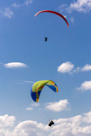 Two parachutes gliding in the sky with white cloudsの写真素材