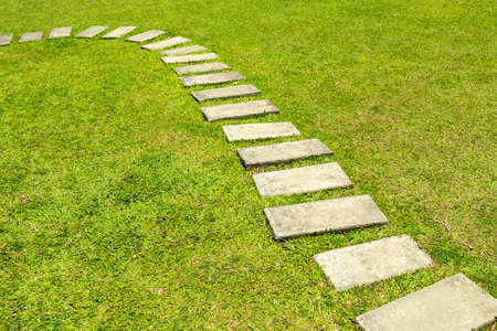 Stone tile pavement on green grass lawnの写真素材