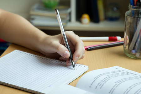 A hand taking or writing notes from a book, close up