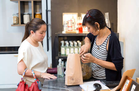 Manila, Philippines - August, 4, 2016: A woman is packing a purchase for a female customer at the cashier counterのeditorial素材