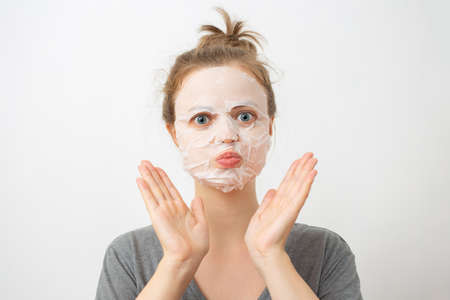 Young caucasian woman with wrinkled white facial mask on her faceの写真素材