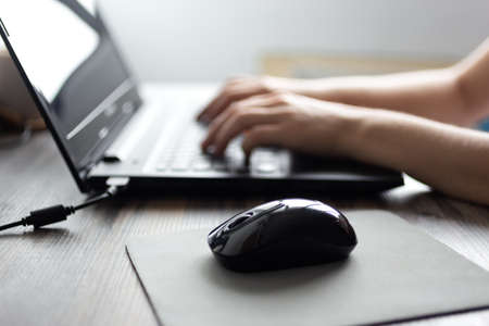 Hands typing quickly on black laptop computer keyboardの写真素材