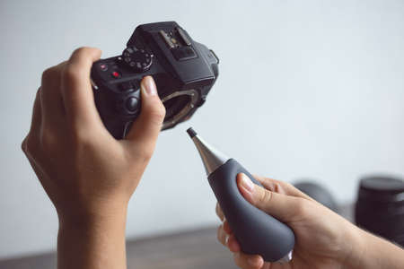 Two hands cleaning digital camera sensor from dust with air blowerの写真素材