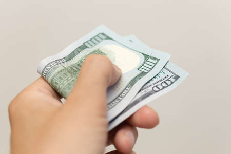 Hand holding cash banknote of one hundred new us dollars paying bills, payment procedure or bribe,...