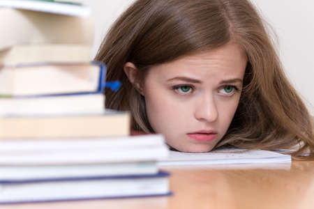 Young caucasian girl woman with many books study at school or university, looks tired, stressed or...