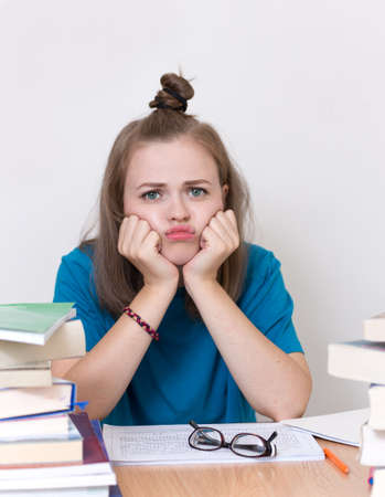 Young caucasian girl woman with many books study at school or university, looks tired, stressed or exhaustedの写真素材