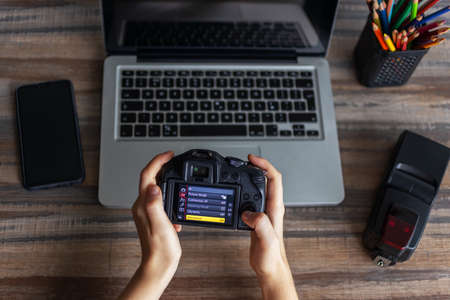 Manila, Philippines - October, 5, 2019: Photographer or stock photography concept, digital black camera in hands near laptop from above, flat lay deskのeditorial素材