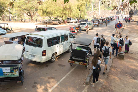 Siem Reap, Cambodia - January 30, 2017: Group of many tourists, tuktuks and cars walking around...