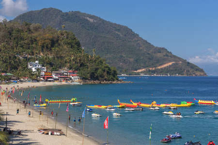 Puerto Galera, Philippines - April 4, 2017: Sea, blue sky, palms, tourists and boats in White beach, Sabang.のeditorial素材