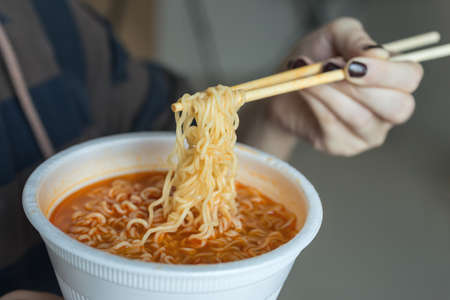 Bowl of instant noodles ramen in hands with chopsticks, close upの写真素材