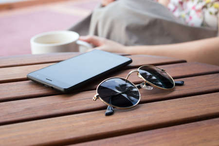 Phone and sunglasses on wooden table, close upの写真素材
