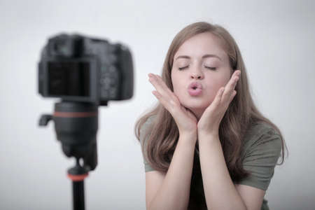 Smiling young caucasian girl woman making a video blog (vlog) with cameraの写真素材